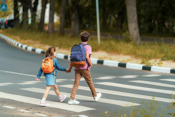 children holding hands crossing a street